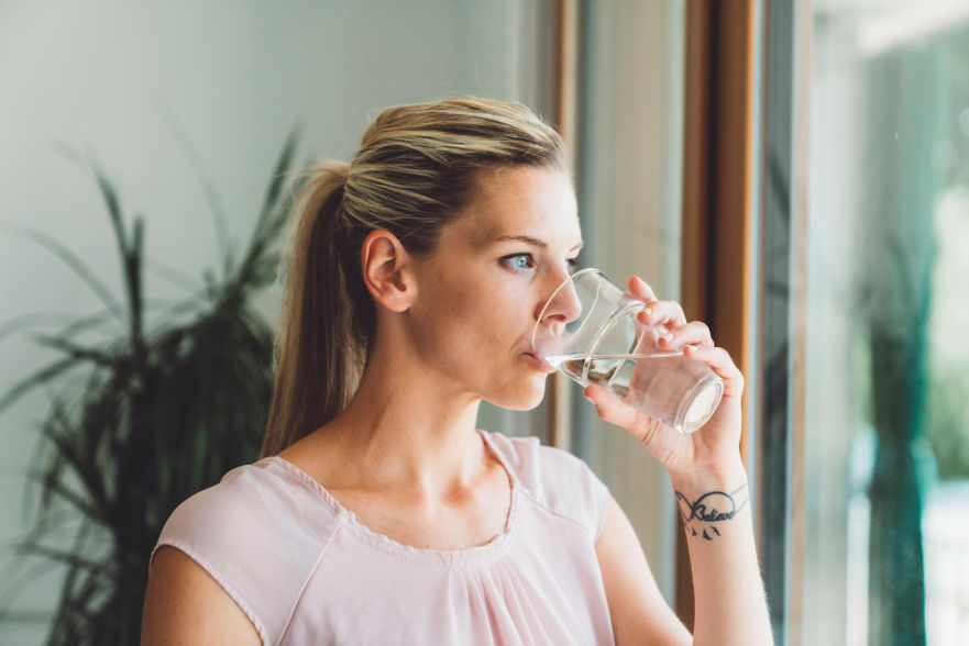 Mujer de perfil bebiendo un vaso de agua
